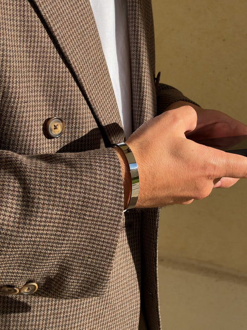 Jonc ELIO STEEL en acier poli miroir porté au poignet avec une veste en laine